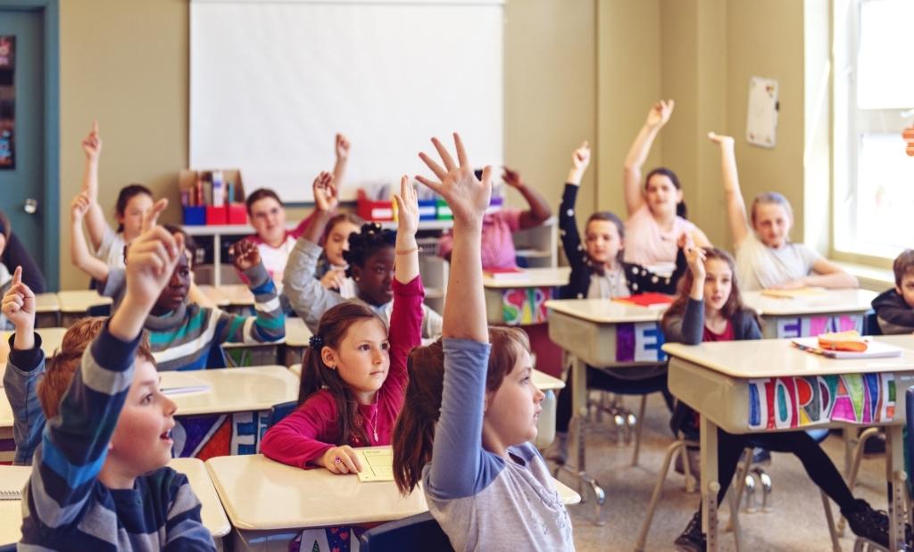 alunos com as mãos levantadas participando ativamente da aula.
