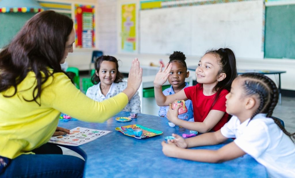 professora interage de forma positiva com crianças durante atividade lúdica na escola.