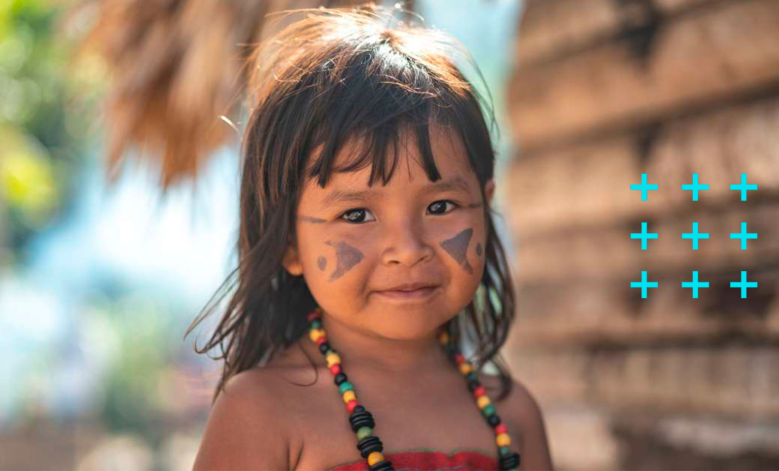 Criança indígena sorri para a foto.