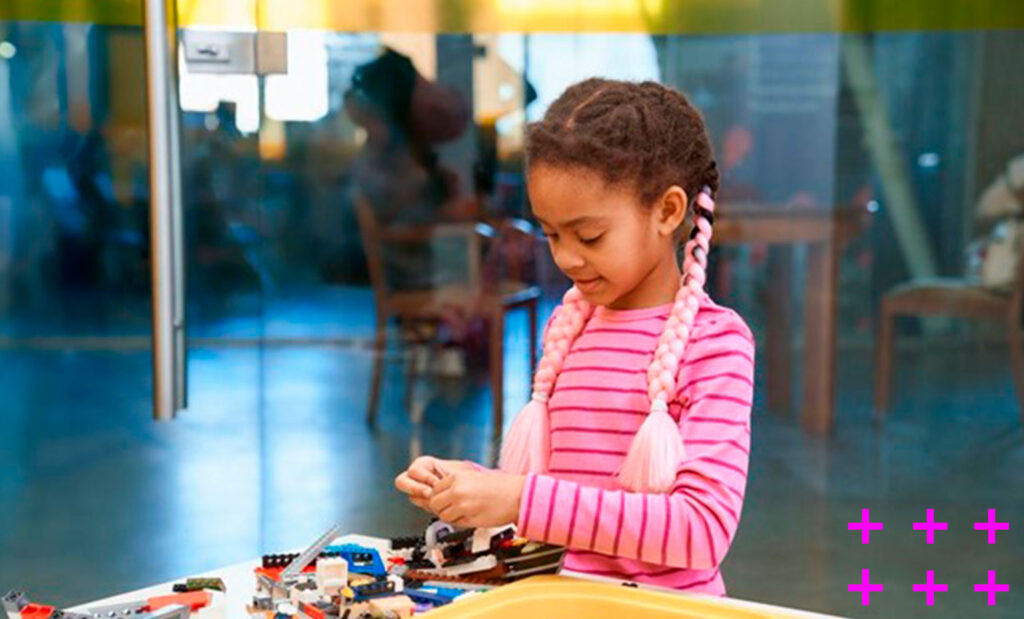 garotinha negra de 8 anos brincando com peças de montar na escola.