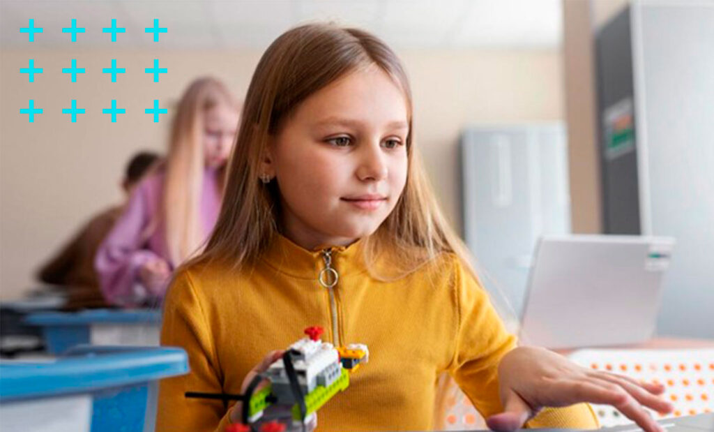 garotinha de 10 anos utilizando um notebook e peças eletrônicas para construir um robô.
