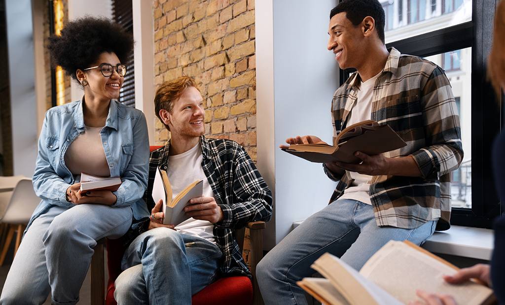 Três estudantes conversando na biblioteca da escola.