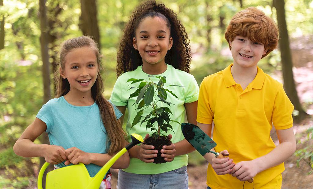 Crianças segurando plantando árvores no parque.