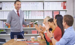 Diretor escolar em sala de reunião conversando com outros gestores da escola.