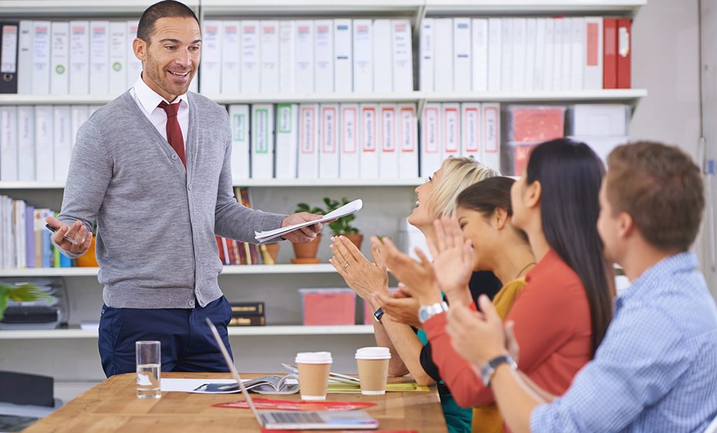 Diretor escolar em sala de reunião conversando com outros gestores da escola.