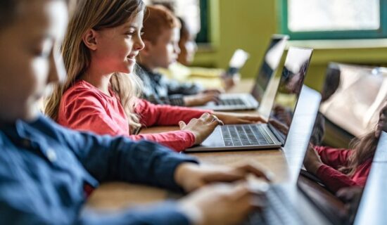 crianças utilizando laptops em sala de aula