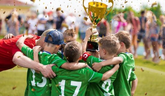 equipe infantil de futebol comemorando com troféu após campeonato.